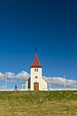 Mädchen, das an einer kleinen Kirche vorbeigeht; Langaholt, Island