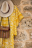 Clothes and accessories hanging on display against a stone wall; Alcudia, Mallorca, Balearic Islands, Spain