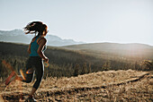 Eine Frau läuft auf einem Pfad in den Rocky Mountains, in der Nähe von Hinton; Alberta, Kanada.