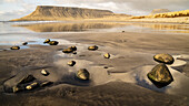 Felsen am nassen schwarzen Sandstrand entlang der isländischen Küste mit Klippen, die sich im Wasser spiegeln, in der Nähe des Kirkjufell; Grundarfjorour, Island