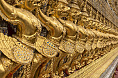 Goldene Skulpturen von Fabelwesen an der Wand des Wat Phra Kaew; Bangkok, Thailand.