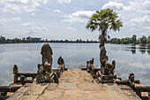 Statues and palm tree on stone jetty, Srah Srang, Angkor Wat; Siem Reap, Siem Reap Province, Cambodia