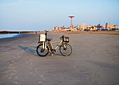 Fishermanâ€™s bicycle on Coney Island Beach with Luna park in background; New York City, New York, United States of America