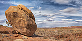 Eine Frau hängt an einem Felsbrocken im Valley of the Gods; Utah, Vereinigte Staaten von Amerika.