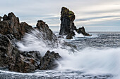 Wellen brechen gegen die Küste des Strandes Djupalonssandur bei Sonnenuntergang, Halbinsel Snaefellsness; Island