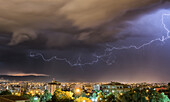 Stürmischer Himmel und Blitze über einer Stadt bei Nacht; Cochabamba, Bolivien