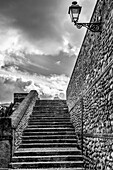 Steps and a stone wall with a mounted light and cloudy sky; Antequera, Malaga, Spain