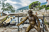 Fischerskulptur mit Münzen in der Hand in einem Hafen; Opatija, Gespanschaft Primorje-Gorski Kotar, Kroatien.