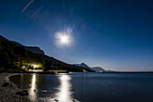 Makarska Riviera at night with the bright moonlight casting light on the tranquil water along the coastline; Dalmatia, Croatia