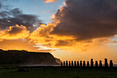 Die fünfzehn Moais von Tongariki vor dem leuchtenden Himmel bei Sonnenaufgang; Osterinsel, Chile.
