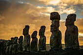 Die fünfzehn Moais von Tongariki in Nahaufnahme in abnehmender Perspektive vor einem bunten Sonnenaufgang; Osterinsel, Chile