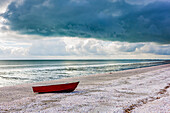 Red boat on shell beach; North Island, New Zealand