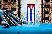 Kubanische Flagge und blaues Auto auf den Straßen von Havanna; Havanna, Kuba