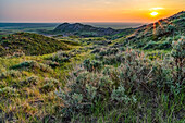 Weite Landschaft, die sich bei Sonnenuntergang im Grasslands National Park bis zum Horizont erstreckt; Val Marie, Saskatchewan, Kanada