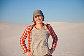 Porträt einer jungen Frau, die auf dem weißen Sand vor blauem Himmel steht, White Sands National Monument; Alamogordo, New Mexico, Vereinigte Staaten von Amerika.