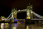 Tower Bridge bei Nacht beleuchtet und reflektiert im ruhigen Wasser der Themse; London, England.