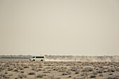 Ein Fahrzeug fährt auf einer staubigen Straße, Etosha-Nationalpark; Namibia.