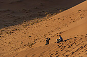 Couple taking photographs on Dune 45, Sossusvlei, Namib Desert, Namib-Naukluft National Park; Namibia