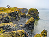 Rugged coastline of the Snaefellsnes Peninsula with a lone house along the cliffs in the mist; Snaefellsbaer, Western Region, Iceland