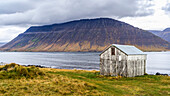 Verwittertes Gebäude am Ufer eines Fjords im Nordwesten Islands in der Gemeinde Isafjarourbaer; Isafjarourbaer, Region Westfjorde, Island.