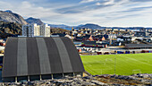 Ein Sportplatz und ein Gebäude mit Blick auf ein Viertel und die Berge; Nuuk, Sermersooq, Grönland