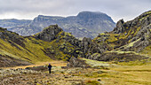 Ein Wanderer auf einem Pfad mit einer zerklüfteten, weiten Landschaft im Hintergrund; Grimsnes- og Grafningshreppur, Südliche Region, Island