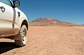 Allradfahrzeug von der Seite gesehen und mit Geländereifen vor hochgelegener Wüste und Bergen im Hintergrund; Potosi, Bolivien