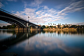 Spiegelung eines Flusses und der Guadalquivir-Brücke in der Abenddämmerung; Sevilla, Andalusien, Spanien.