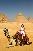 Weibliche Touristin auf einem Kamel, Pyramidenkomplex von Gizeh, UNESCO-Weltkulturerbe; Gizeh, Ägypten.