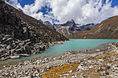 One of Gokyo's sacred turquoise colored lakes, on a sunny autumn day surrounded by fall colored tundra in Sagarmatha National Park; Solokhumbu District, Nepal