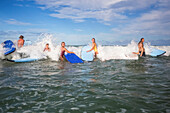 Surfer spielen herum und haben eine gute Zeit mit Freunden, während sie im Wasser sind und in den Wellen am Arrawarra Beach surfen; Arrawarra, New South Wales, Australien