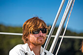 Nahaufnahme eines Mannes mit Sonnenbrille auf einer Katamaran-Bootstour durch den neuseeländischen Abel-Tasman-Nationalpark; Tasman, Neuseeland.