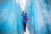 Reisende erkunden Neuseelands berühmten Franz-Josef-Gletscher. Blaues Eis, tiefe Gletscherspalten, Höhlen und Tunnel kennzeichnen das sich ständig verändernde Eis; Westküste, Neuseeland