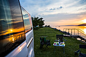 A group of travellers set up camp alongside of Lake Balaton at sunset; Zamardi, Somogy County, Hungary