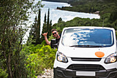 Mann hängt aus dem Autofenster und fährt mit dem Wohnmobil zu einem abgelegenen Strand an der kroatischen Küste; Zaton Doli, Gespanschaft Dubrovnik-Neretva (Dubrovacko-neretvanska zupanija), Kroatien