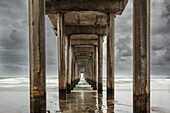 Stürmischer Himmel und der sich wiederholende Blick auf die Zementsäulen unter dem ikonischen Scripps Pier im Pazifik bei San Diego; La Jolla, San Diego County, Kalifornien, Vereinigte Staaten von Amerika
