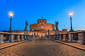 Ponte Sant'Angelo, die den Tiber überspannt und von Engelsstatuen gesäumt ist, die in der Abenddämmerung von Laternen beleuchtet werden und zur Engelsburg (Mausoleum des Hadrian) führen; Rom, Latium, Italien.