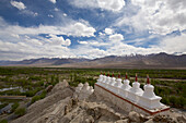 Weiß getünchte buddhistische Stupas (in der tibetischen Kultur als Chortens bekannt) in einer Reihe auf einem Berggipfel bei den Ruinen des Klosters Shey oberhalb des Industals, im Himalaya-Gebirge von Ladakh, Jammu und Kaschmir; Shey, Ladakh, Indien