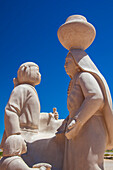 Nahaufnahme einer weißen Steinskulptur einer traditionellen Familie des Acoma-Volkes im Innenhof des Sky City Cultural Center und des Haak'u-Museums vor blauem Himmel in der alten indianischen Gemeinschaft des Acoma Pueblo; Acoma, New Mexico, Vereinigte Staaten von Amerika.