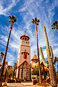 The impressive bell tower and the stone and brick exterior of The Chapel of St George with landscaped grounds at St Anthony's Greek Orthodox Monastery; Florence, Arizona, United States of America