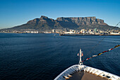 Close-up of the bow of a ship in Table Bay looking towards the Port of Cape Town and the majestic Devil's Peak and Table Mountain rising above the city skyline and waterfront in the morning light from the sea; Cape Town, Cape Province, South Africa