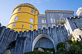 Die auf einem Hügel gelegene Burg Palacio Da Pena mit ihren bunten Türmen und der Steinmauer in den Sintra-Bergen; Sintra, Bezirk Lissabon, Portugal.