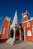 Der rote Uhrenturm und der kegelförmige Pavillon auf einer Terrasse des auf einem Hügel gelegenen Schlosses Palacio Da Pena in den Sintra-Bergen; Sintra, Bezirk Lissabon, Portugal.