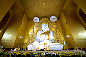 Innenraum des Mahagandhayon-Klosters mit einer weißen Marmorstatue eines sitzenden Buddhas mit vergoldetem Zubehör und umgeben von goldenen Wänden; Amarapura, Mandalay City, Mandalay, Myanmar (Burma).