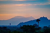 Silhouette of the mountains and pagodas with first light of sunrise over the Plain of Bagan landscape at dawn; Bagan, Mandalay, Myanmar (Burma)