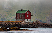 Traditional fishing village house next to the shoreline in Lofoten; Lofoten, Arctic Circle, Norway