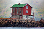 Traditional fishing village house next to the shoreline in Lofoten; Lofoten, Arctic Circle, Norway