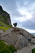The dramatic coastal mountain and rock landscape of Uttakleiv Beach in Lofoten, Norway, with the naturally formed heart-shaped rock balancing on a large boulder; Lofoten, Norway