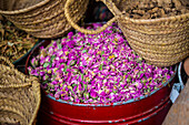 Close-up of metal container with dried rose petals and baskets of spices for sale in the spice souk in the Medina of Marrakesh; Marrakesh, Marrakesh-Safi, Morocco
