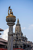 Säulenstatue von König Yoganarenda Malla mit dem Krishna-Mandir-Tempel im Shikhara-Stil im Hintergrund am Patan Durbar Square in der alten Stadt Patan (oder Lalitpur), die zwischen dem 16. und 18. Jahrhundert von den Newari Hindu Mallas im Kathmandu-Tal errichtet wurde; Patan (Lalitpur), Kathmandu-Tal, Nepal.